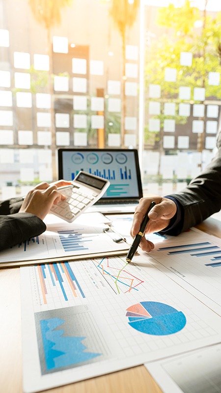 Business people doing business in finance and calculating, analyzing, graphing on costs of investments, real estate and more, tax system on the desk with laptops and calculators with documents. two people discussing finances
